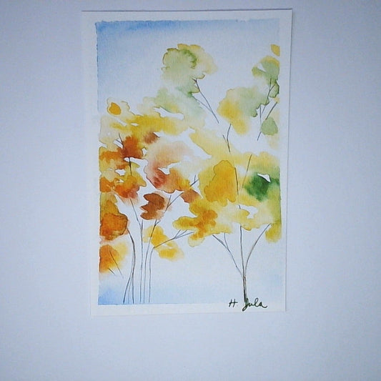 A vertical watercolor painting of yellow and orange trees on a light blue background, mounted on a white wall.